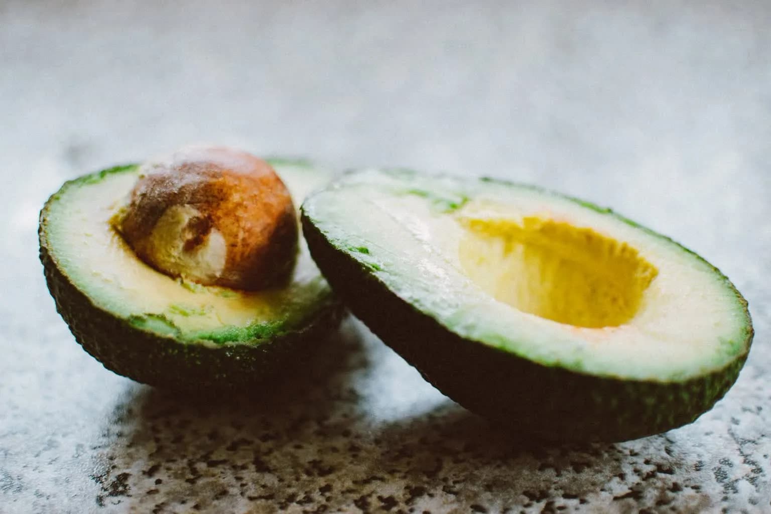 A halved avocado showing its pit and bright green flesh