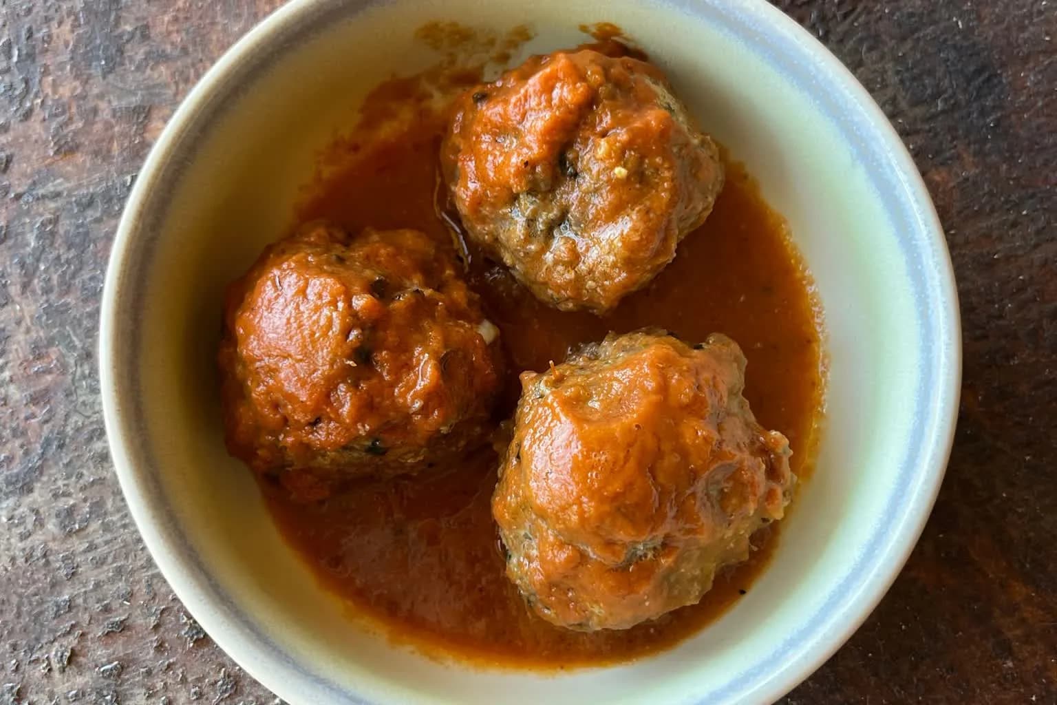 Three whole meatballs holding together in tomato sauce